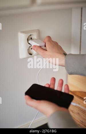 Hands plugging in cell phone charger Stock Photo