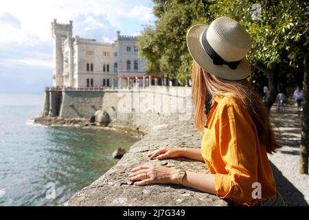 Travel in Italy. Back view of beautiful girl visiting Miramare Castle in Trieste, Italy. Stock Photo
