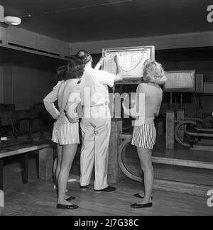 Bowling in the 1950s. A man with three young women in a bowling alley. They are dressed in short striped skirts and jumpers. The three girls are all theatre actresses; Ingrid Björk, UllaCarin Rydén and Brita Ulfberg. Ewert Ekström shows is instructing them in bowling. He was a professional bowler player in the 1930s and is at this time an instructor and owner of the bowling club.  1950. Sweden Kristoffersson ref AY36-8 Stock Photo
