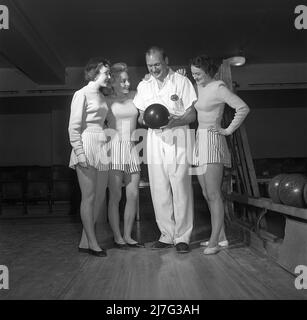 Bowling in the 1950s. A man with three young women in a bowling alley. They are dressed in short striped skirts and jumpers. The three girls are all theatre actresses; Ingrid Björk, UllaCarin Rydén and Brita Ulfberg. Ewert Ekström shows is instructing them in bowling. He was a professional bowler player in the 1930s and is at this time an instructor and owner of the bowling club.  1950. Sweden Kristoffersson ref AY36-1 Stock Photo