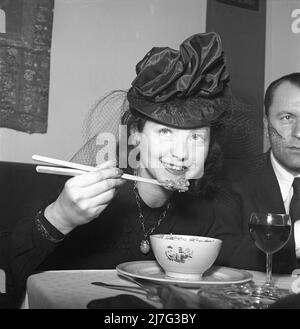 Chinese food being served for the first time ever in a swedish restaurant 1944. It is actress Marguerite Viby who looks as if she can handle the chopsticks and enjoys the novelty food. The restaurant Berns in Stockholm has four chinese chefs cooking traditional chinese cuisine for the first time in a swedish restaraunt. Sweden Kristoffersson G53-5 Stock Photo