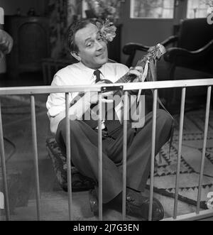 Father in the 1940s. Actor Åke Söderblom, 1910-1965 tries his best at amusing his son from outside the playpen playing the guitar. Sweden 1949 AN92-2 Stock Photo