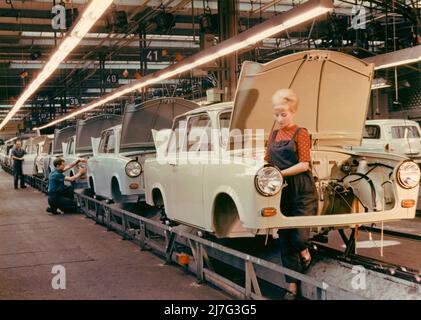 The Trabant car. East German VEB Sachsenring Automobilwerk. Trabant began manufacturing 1957 and production lasted until 1991. A total of 3 051385 Trabants were made. Trabant was developed as East Germanys answer to Volkswagen and the vision of a car for the people. It was called Trabbi or Trabi and became the most common car in East Germany. Trabant came to be somewhat of a symbol for East Germany during the time of the fall of the Berlin wall. Picture taken in Trabant carfactory in Sachsen in the 1960s. The young woman standing at the assembly line has the typical hairdo of the 1960s, the Be Stock Photo