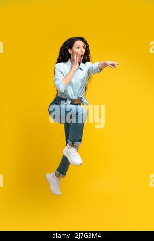 Excited woman pointing finger aside at copy space Stock Photo