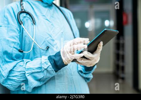Close up shot of surgeon hands using smart tablet at hospital corridor - concept of checking reports, technologyand healthcare or medical treatment Stock Photo