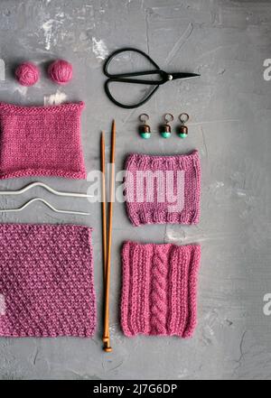 Top view: knitting accessories and samples of knitted products lie on a gray concrete background. Place for inscription. Stock Photo