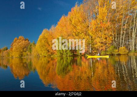 Kayak and autumn reflections in Kellands Pond, near Twizel, Mackenzie District, North Otago, South Island, New Zealand (model released) Stock Photo