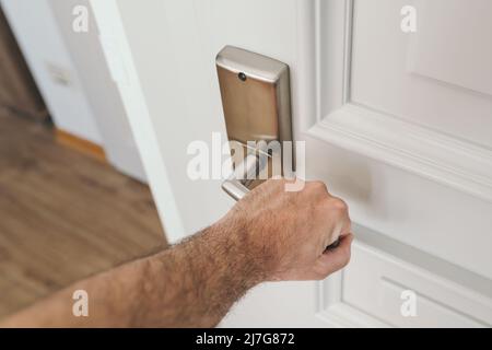 Man opening apartment door, closeup of male hand on handle, selective focus Stock Photo
