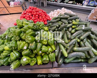 Grovetown, Ga USA - 04 20 22: Green peppers Cucumbers and tomatoes on display Stock Photo