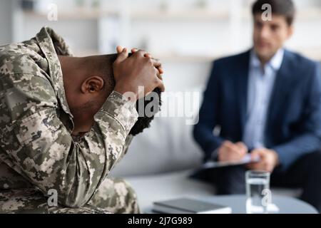 Depressed black soldier visiting psychotherapist at clinic Stock Photo