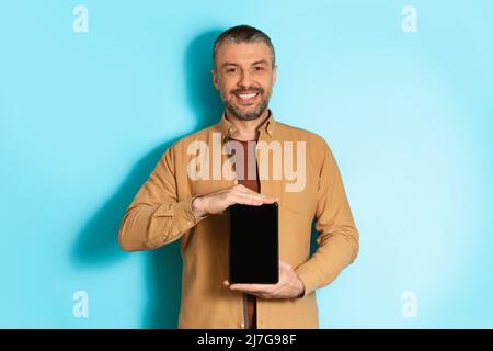 Male Holding Tablet Computer With Empty Screen On Blue Background Stock Photo