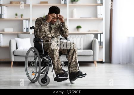 Unhappy black man sitting in wheelchair, wearing military uniform Stock Photo