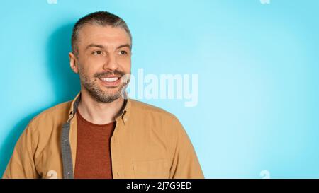 Portrait Of Happy Middle Aged Male Looking Aside, Blue Background Stock Photo