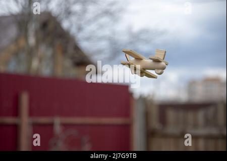 A small wooden toy airplane in the air. flying above the clouds in the sky. Stock Photo