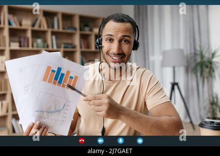 Happy arab businessman making teleconference with colleagues from home, showing reports with graphs and charts Stock Photo