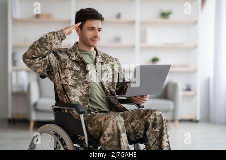 Patriotic veteran sitting in wheelchair, using laptop Stock Photo