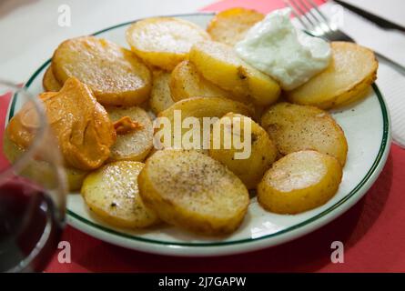 Traditional Spanish fried potatoes Patatas bravas served with cheese sauce and spicy sauce with paprika and chili Stock Photo