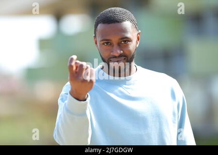 Front view portrait of a man with black skin gesturing come here in the street Stock Photo