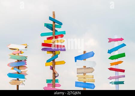Colorful wooden direction arrow signs on wooden poles Stock Photo
