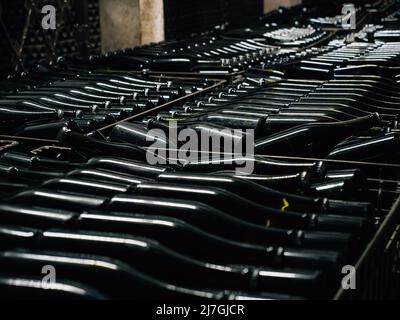 Bottles of wine aging covered with old dust in underground cellar close up. Stock Photo