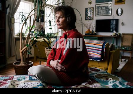 Depressed senior woman sitting alone on bed at home Stock Photo