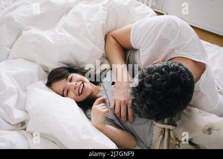 Playful father playing with daughter lying on bed at home Stock Photo