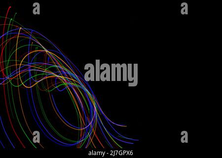 Swirling pattern created in the air with bright neon coloured motion trails on a black background with copy space Stock Photo