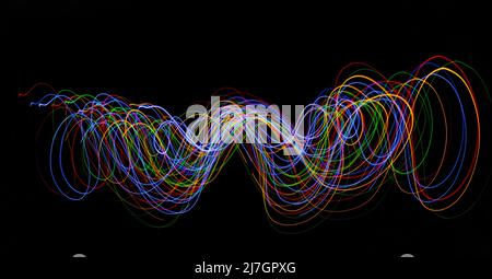 Swirling pattern created banner with bright neon coloured motion trails on a black background with copy space Stock Photo