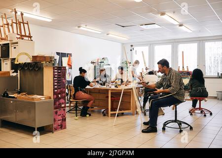 Male and female students practicing painting in art class Stock Photo
