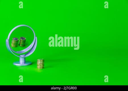 Single gold coloured coin stack reflecting two stacks in a mirror saving concept on a bright green background Stock Photo
