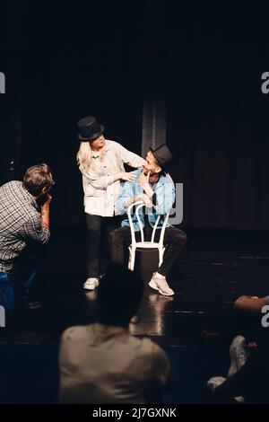 Full length of actress rehearsing with man sitting on chair while rehearsing on stage Stock Photo