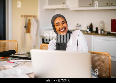 Happy young female freelancer working on laptop at home Stock Photo