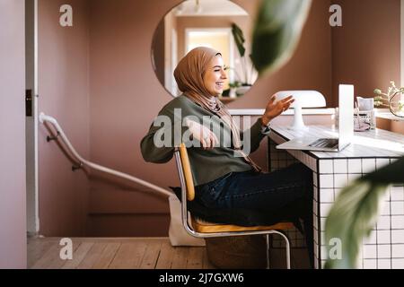 Happy young woman gesturing while video calling through laptop at home Stock Photo