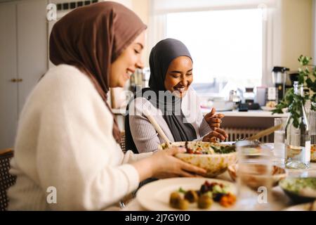 Smiling young woman sitting with friend at dining table Stock Photo