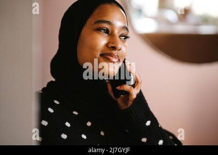 Smiling woman talking on smart phone at home Stock Photo