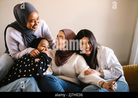 Cheerful women sitting together on sofa at home Stock Photo