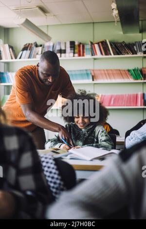 Teacher explaining student while studying in classroom Stock Photo