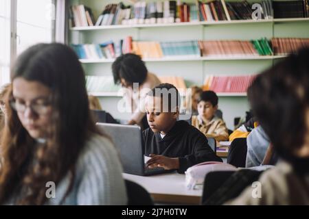 Boy using laptop while e-learning in classroom Stock Photo