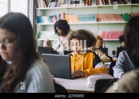 Girl using laptop at desk while studying in classroom Stock Photo