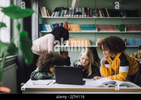 Multiracial students watching laptop while studying in classroom Stock Photo
