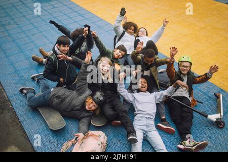 Portrait of school students with hand raised having fun at sports court Stock Photo