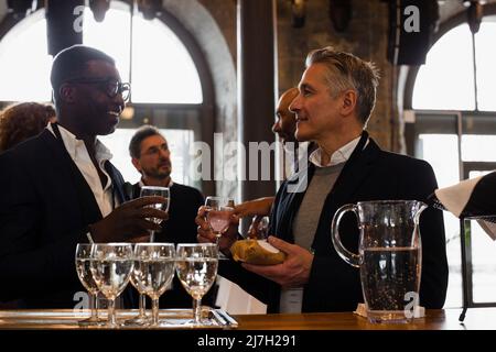 Businessmen holding glasses while discussing with each other during seminar Stock Photo