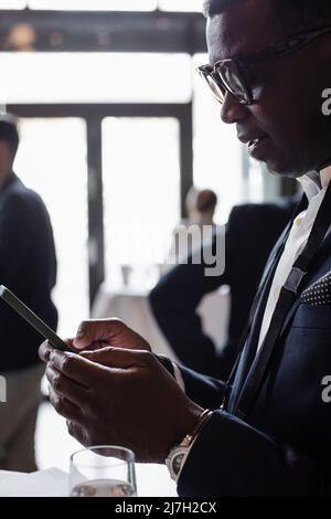 Businessman text messaging through smart phone at seminar Stock Photo