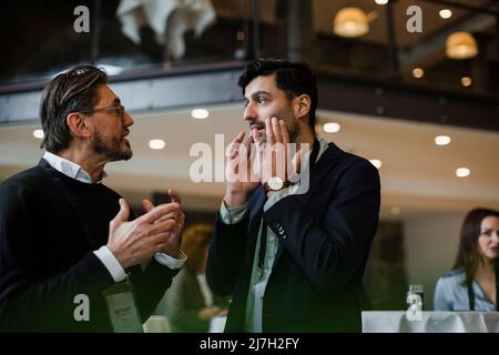 Businessmen gesturing while talking with each other during seminar Stock Photo