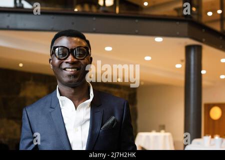 Portrait of smiling businessman wearing blazer in conference center Stock Photo