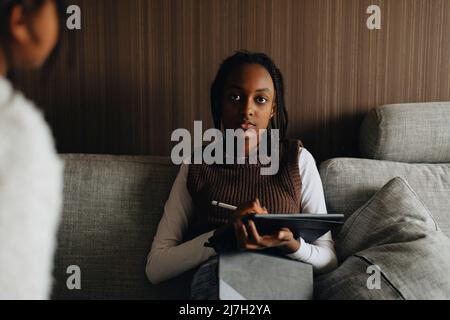 Portrait of girl holding tablet PC while sitting on sofa at home Stock Photo