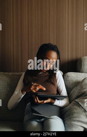 Girl using tablet PC while sitting on sofa at home Stock Photo