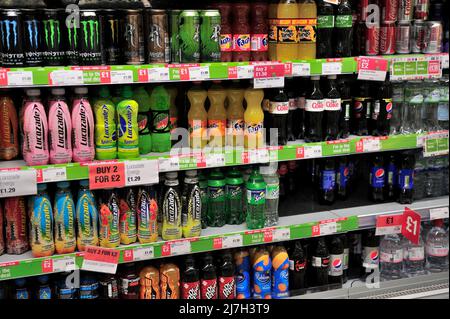 Bottles and cans of soft drinks on supermarket shelves, UK