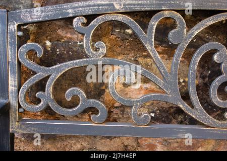 detail of dark grey railings with a stone wall behind Stock Photo
