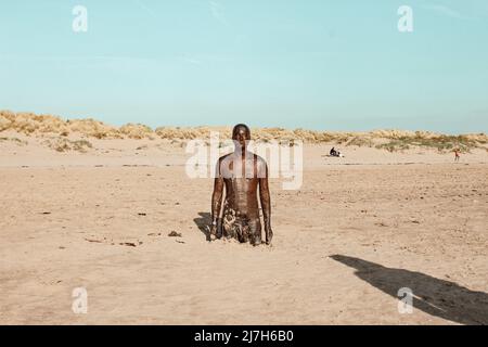 'Another Place' man cast-iron sculpture by Antony Gormley in the sand on Crosby Beach, England Stock Photo